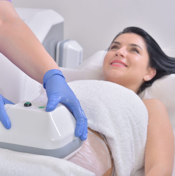 Pretty young woman getting cryolipolyse treatment in professional cosmetic cabinet